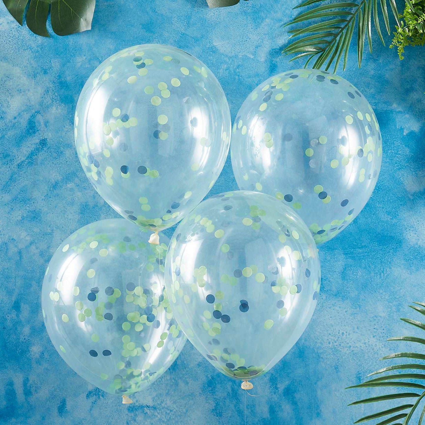 clear balloons with green and blue paper confetti on the inside for a kids dinosaur birthday party theme decorations