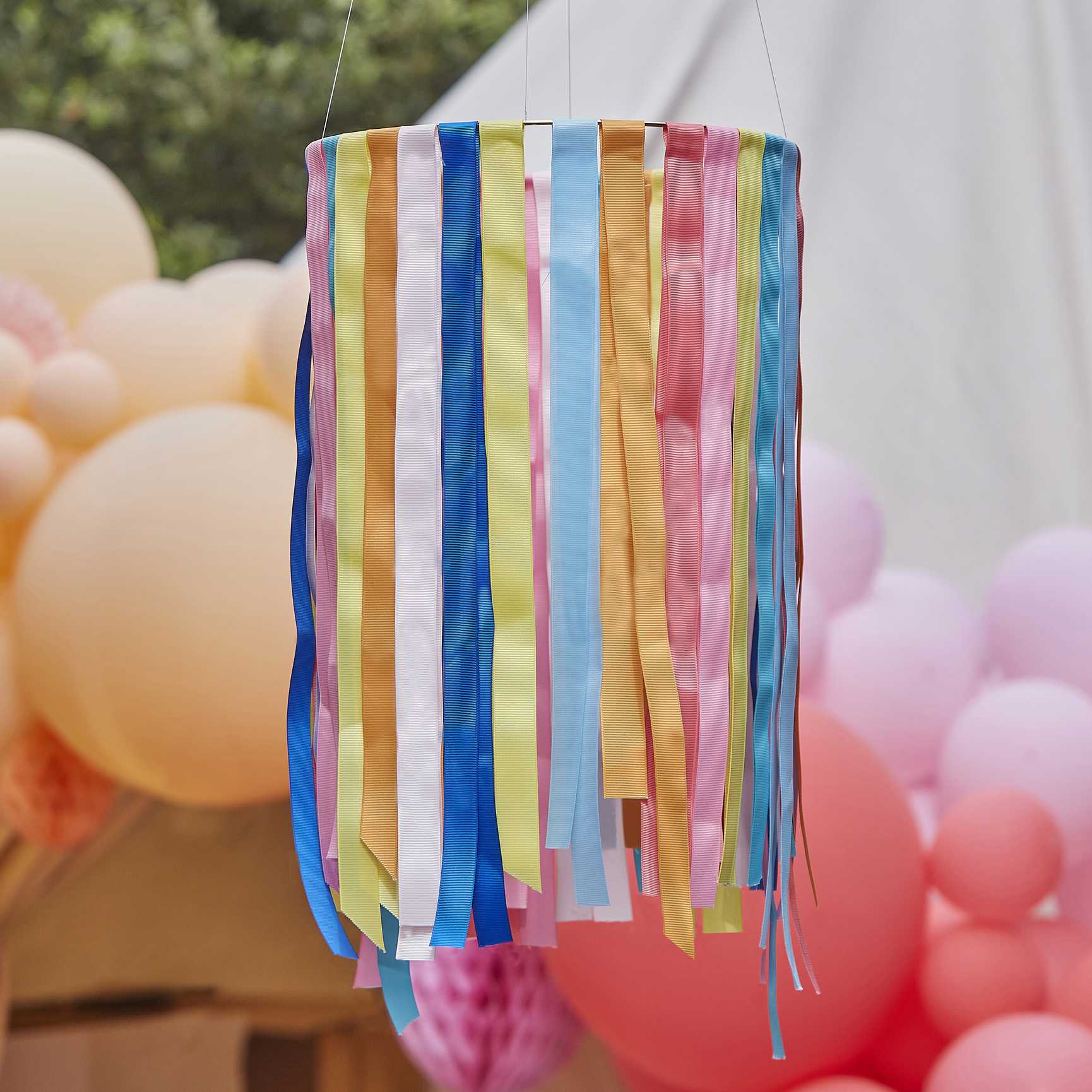 hanging hoops from the ceiling with rainbow multicoloured ribbon streamers hanging from them for party decorations