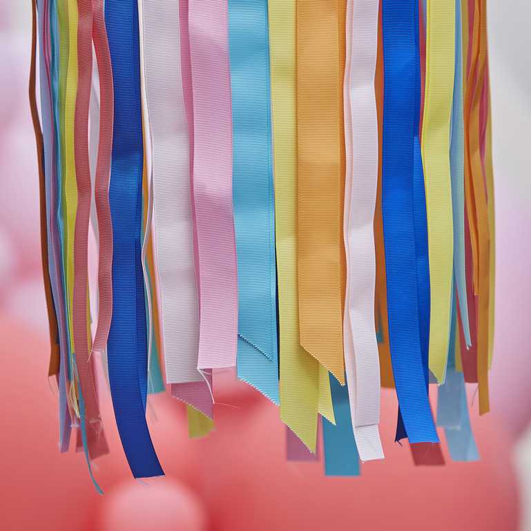 hanging hoops from the ceiling with rainbow multicoloured ribbon streamers hanging from them for party decorations