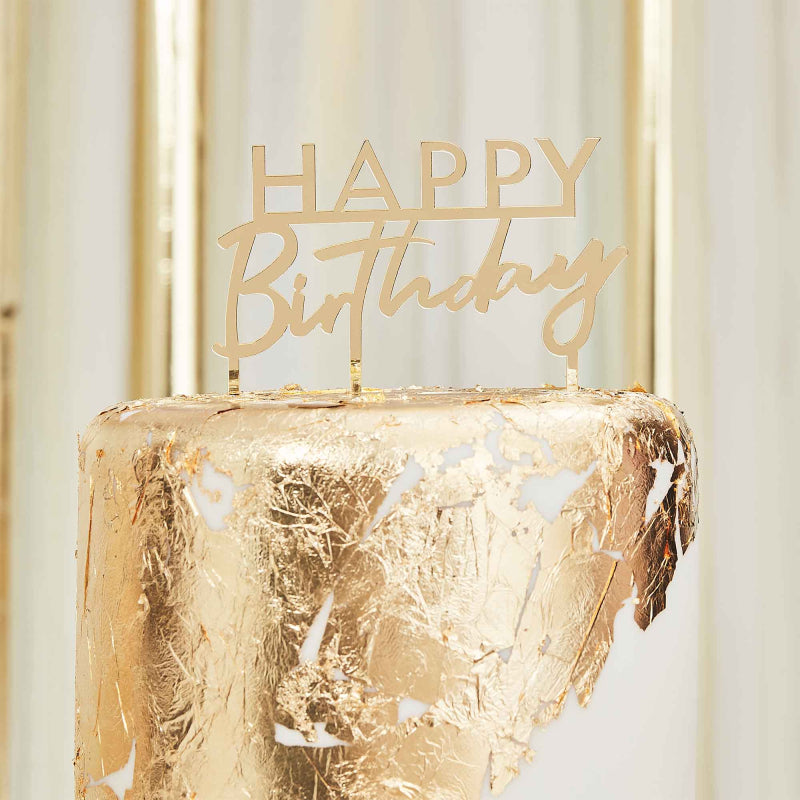 gold acrylic cake topper that reads the words 'happy birthday' for a gold theme birthday party decoration